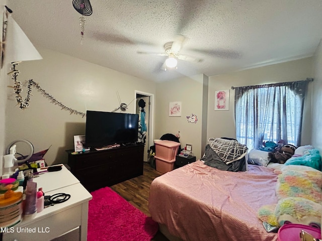 bedroom with ceiling fan, a textured ceiling, and dark hardwood / wood-style floors