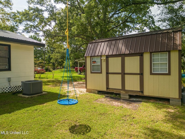 view of outdoor structure featuring a lawn and central AC