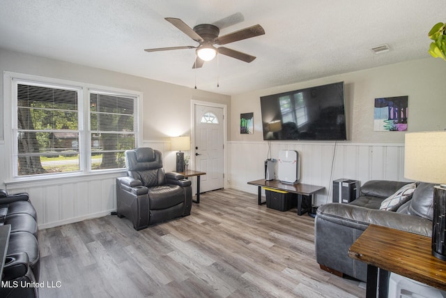 living room with ceiling fan, a textured ceiling, and light hardwood / wood-style flooring