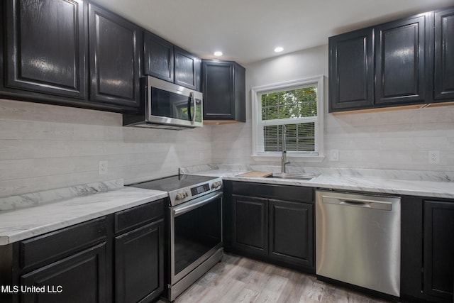 kitchen featuring decorative backsplash, light hardwood / wood-style floors, sink, and stainless steel appliances