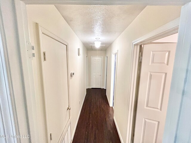 hall featuring a textured ceiling and dark hardwood / wood-style flooring