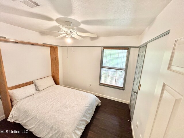 bedroom featuring a closet, dark hardwood / wood-style floors, a textured ceiling, and ceiling fan