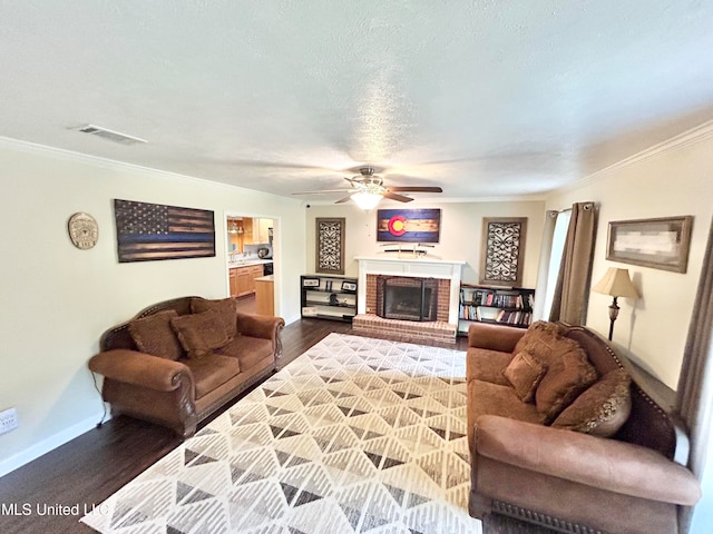 living room featuring crown molding, a fireplace, wood-type flooring, and ceiling fan