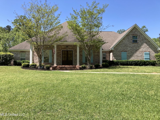 view of front of home featuring brick siding, a front yard, and a shingled roof