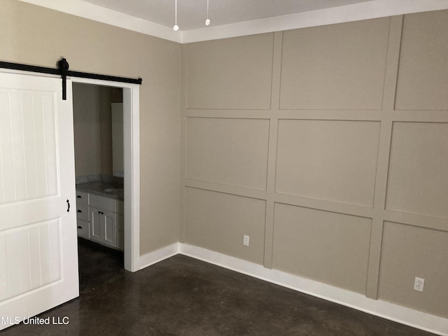 unfurnished bedroom featuring concrete flooring, baseboards, and a barn door