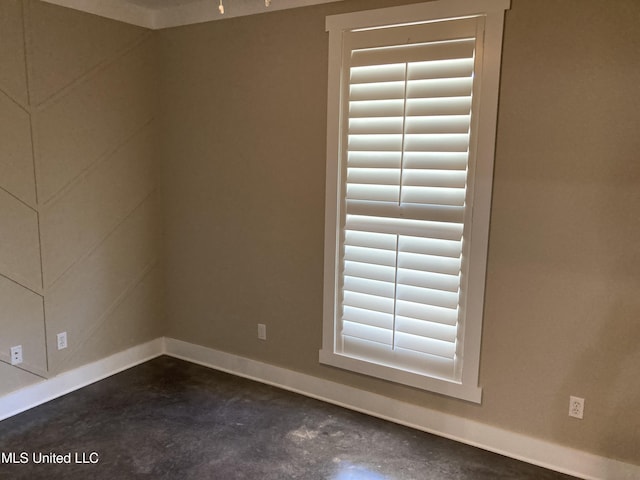 unfurnished room with concrete floors and baseboards