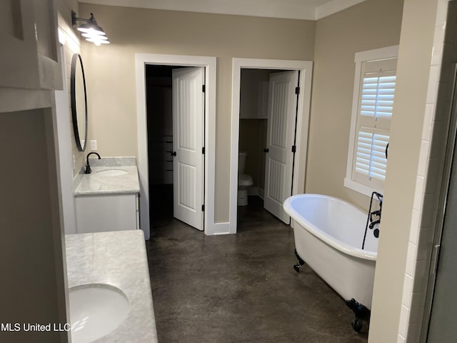 bathroom featuring concrete floors, vanity, a freestanding tub, and toilet