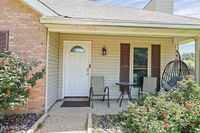 6 Laurie Cv, Byram, MS 39272 - view of exterior entry with covered porch, brick siding, roof with shingles, and a chimney