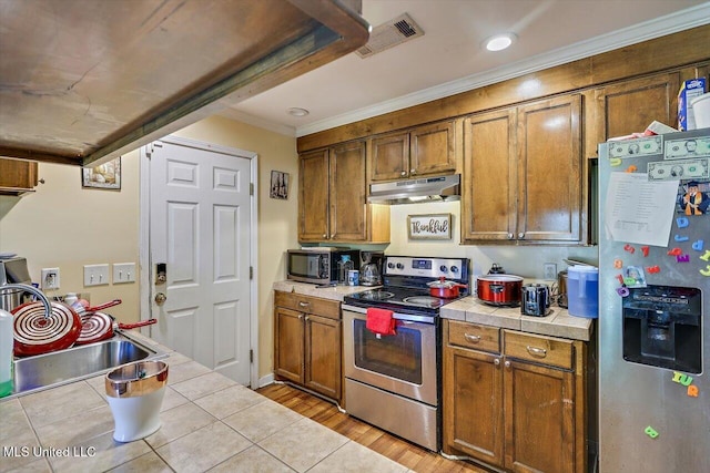 6 Laurie Cv, Byram, MS 39272 - kitchen with appliances with stainless steel finishes, under cabinet range hood, tile countertops, a sink, and ornamental molding