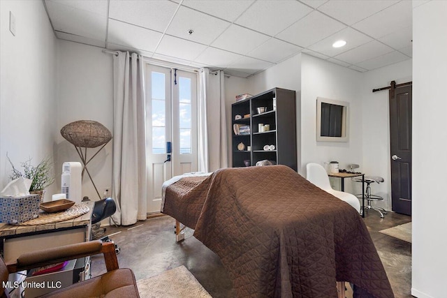 bedroom featuring a paneled ceiling and a barn door