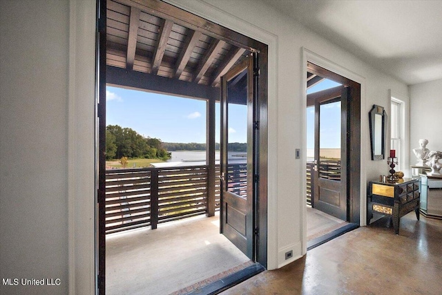 doorway with lofted ceiling with beams, a water view, and concrete floors