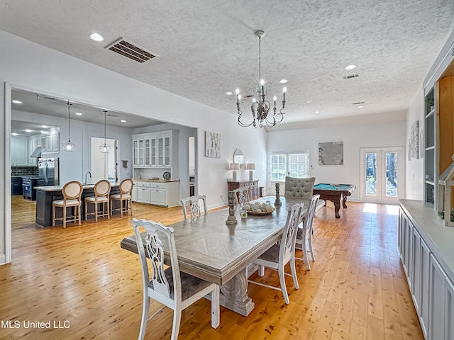 dining area with sink, an inviting chandelier, light hardwood / wood-style flooring, a textured ceiling, and pool table