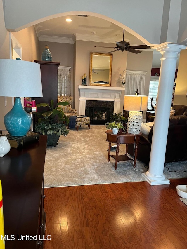 living room featuring ceiling fan, wood-type flooring, ornamental molding, and a fireplace