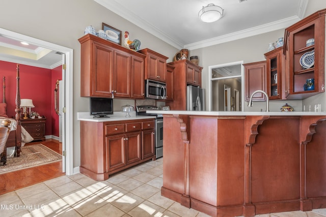 kitchen with appliances with stainless steel finishes, a kitchen breakfast bar, ornamental molding, sink, and light tile patterned floors