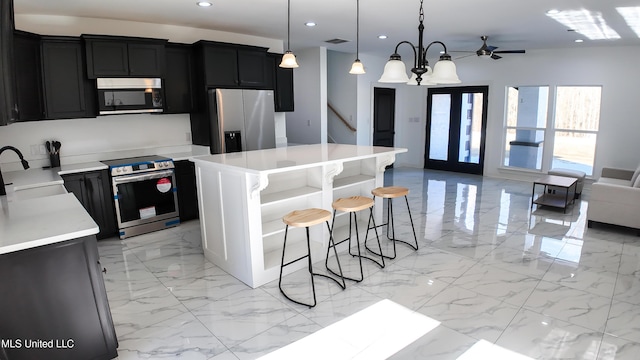 kitchen with pendant lighting, a breakfast bar, appliances with stainless steel finishes, a notable chandelier, and a kitchen island