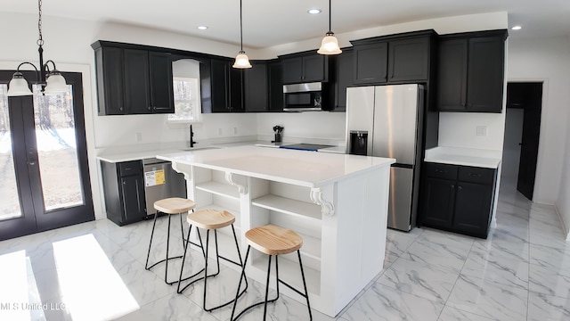 kitchen featuring sink, appliances with stainless steel finishes, a kitchen breakfast bar, a kitchen island, and pendant lighting