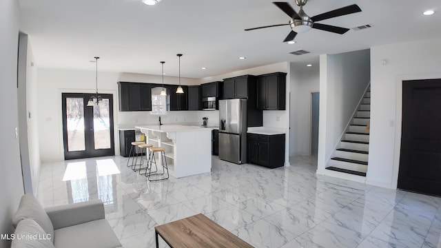 kitchen with a kitchen island, a breakfast bar, stainless steel fridge, hanging light fixtures, and ceiling fan