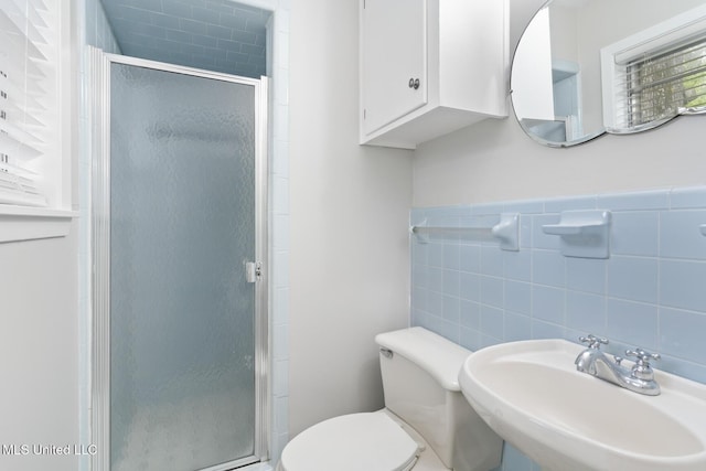 bathroom with toilet, tile walls, a sink, and a stall shower
