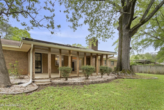back of house with a lawn, a chimney, fence, brick siding, and french doors