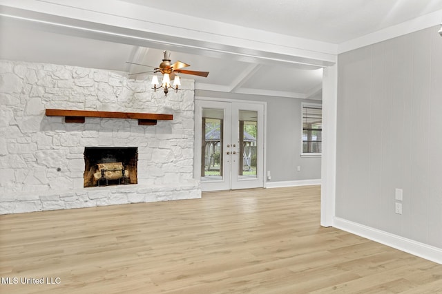 unfurnished living room featuring baseboards, a stone fireplace, ceiling fan, wood finished floors, and french doors