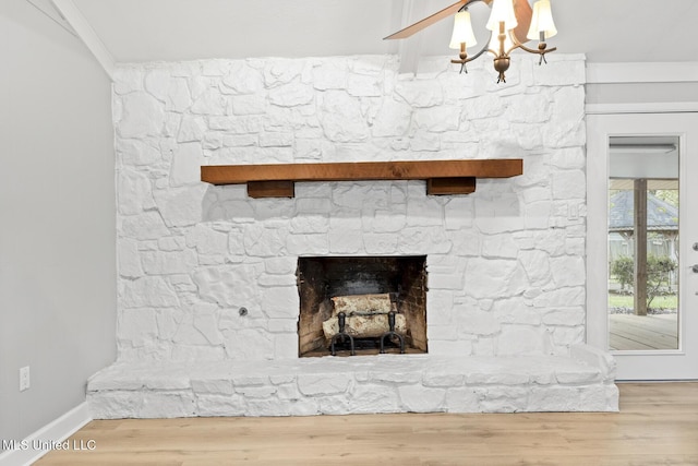 room details featuring baseboards, a chandelier, wood finished floors, and a fireplace