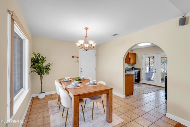 dining room featuring arched walkways, french doors, a notable chandelier, light tile patterned floors, and visible vents