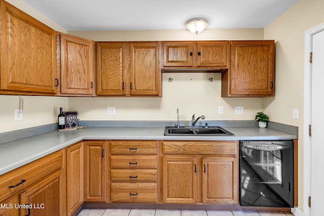 kitchen featuring black dishwasher, brown cabinetry, a sink, and light countertops