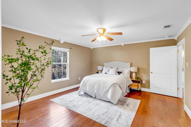 bedroom with hardwood / wood-style flooring, visible vents, baseboards, and crown molding