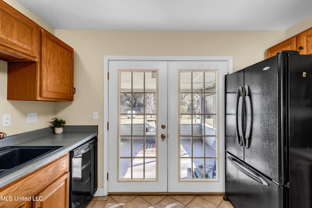 kitchen featuring light tile patterned floors, brown cabinets, french doors, black appliances, and a sink