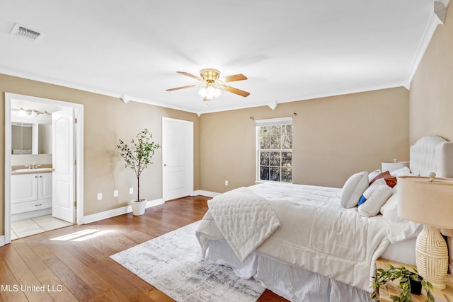 bedroom featuring baseboards, visible vents, ornamental molding, wood finished floors, and a sink