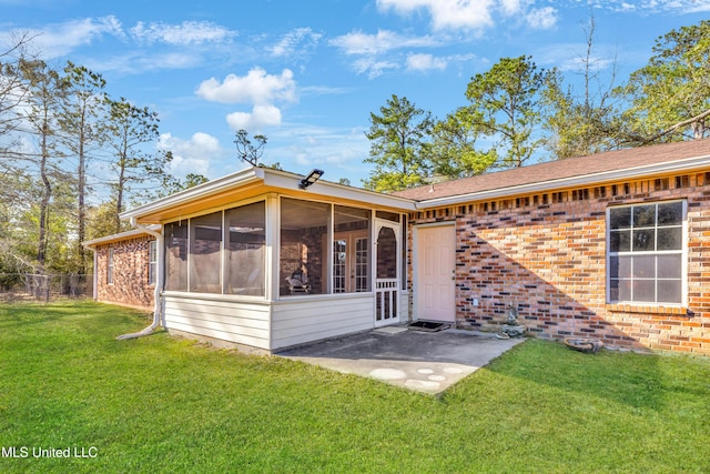 back of property with a sunroom, a patio area, a lawn, and brick siding