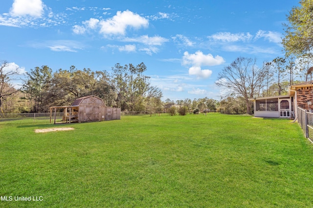 view of yard featuring a sunroom, an outdoor structure, a storage shed, and fence