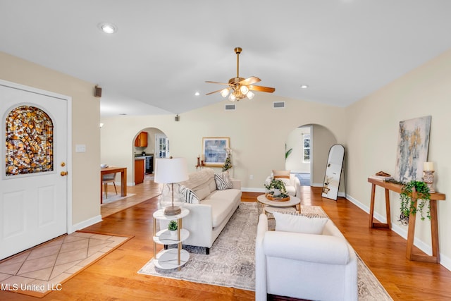 living room with arched walkways, light wood-type flooring, and visible vents