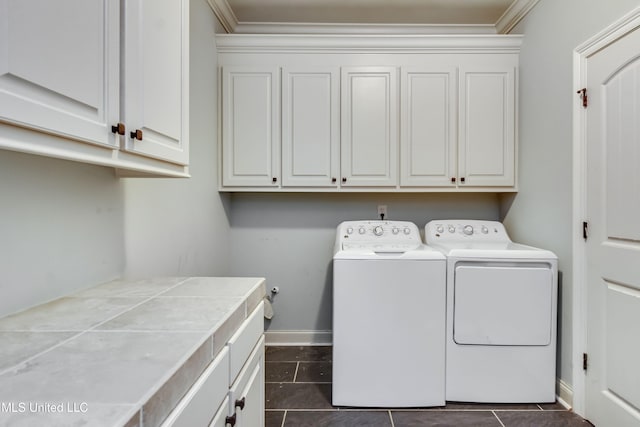 laundry room featuring dark tile patterned floors, cabinets, and washing machine and clothes dryer