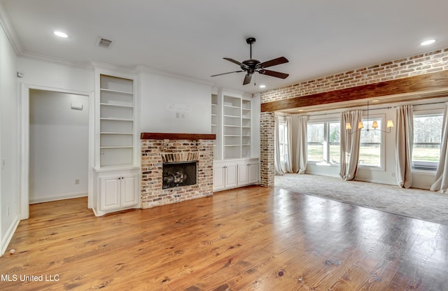 unfurnished living room featuring a brick fireplace, crown molding, light hardwood / wood-style floors, and brick wall