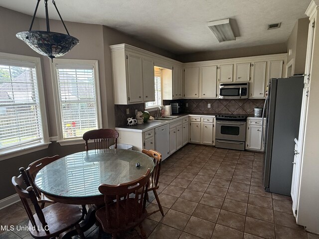 302 Chatfield Cv, Madison, MS 39110 - kitchen featuring stainless steel appliances, tasteful backsplash, dark tile patterned flooring, white cabinets, and a sink