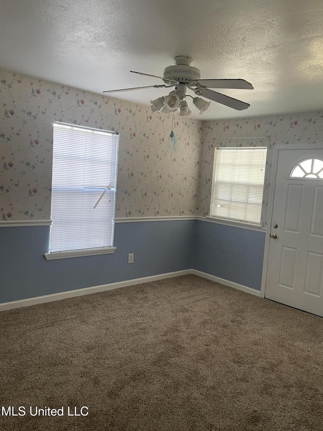 unfurnished room with ceiling fan, a wealth of natural light, a textured ceiling, and carpet flooring