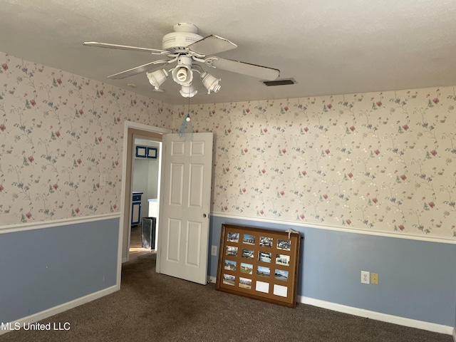 empty room featuring ceiling fan and dark carpet