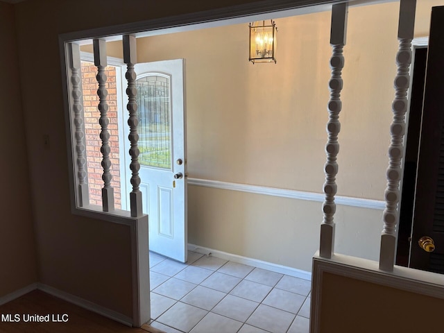 foyer featuring baseboards, a chandelier, and light tile patterned flooring