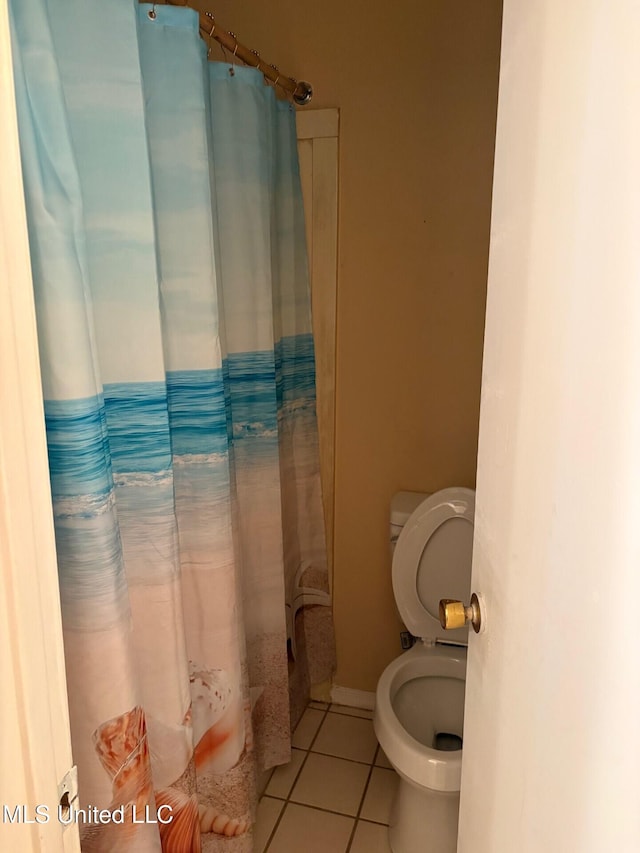bathroom featuring toilet, a shower with curtain, and tile patterned flooring