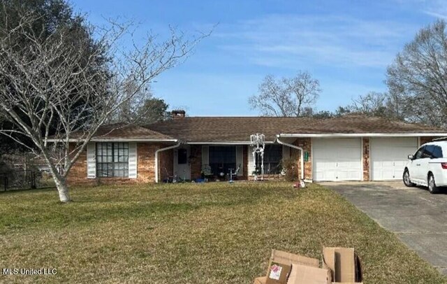 single story home with driveway, a chimney, a front lawn, brick siding, and a garage