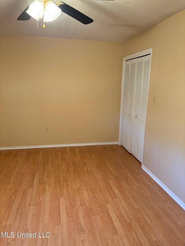 unfurnished bedroom with a closet, ceiling fan, light wood-style flooring, and baseboards