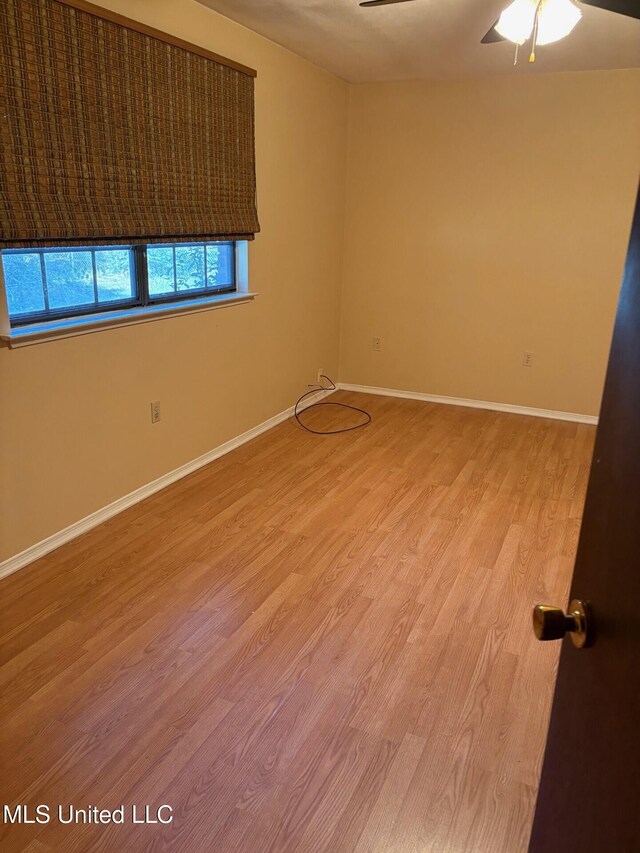 spare room featuring a ceiling fan, baseboards, and light wood-style floors