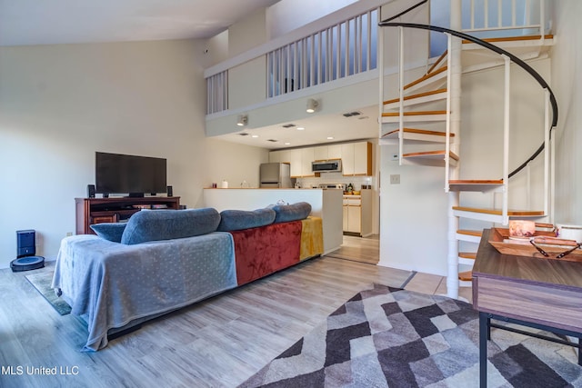 living room featuring high vaulted ceiling and light hardwood / wood-style floors