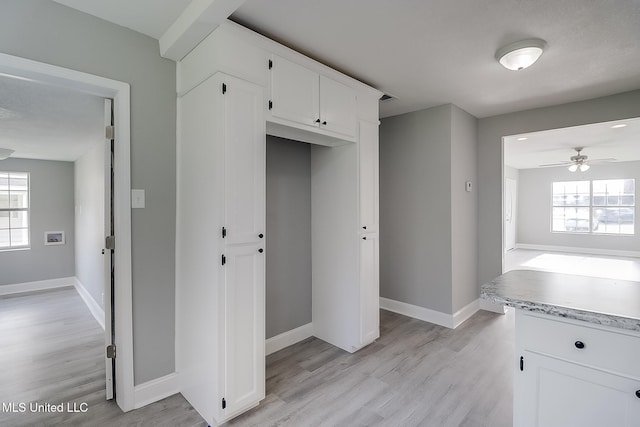 kitchen featuring light wood-type flooring, white cabinetry, a wealth of natural light, and ceiling fan