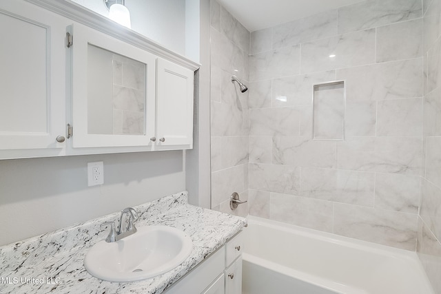 bathroom featuring tiled shower / bath combo and vanity