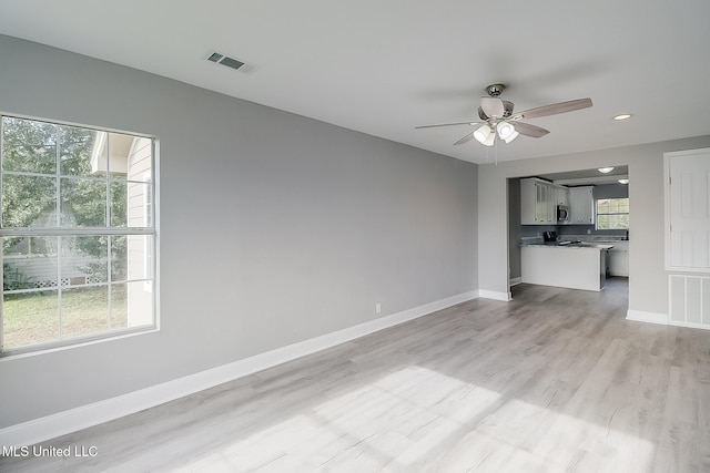 unfurnished living room featuring ceiling fan and light wood-type flooring