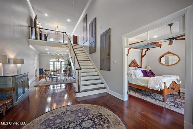 stairway featuring crown molding, wood-type flooring, and ceiling fan with notable chandelier