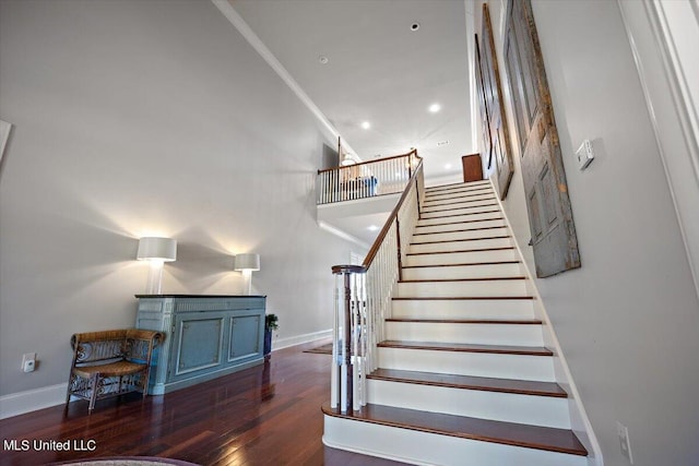 stairs featuring a towering ceiling, hardwood / wood-style flooring, and ornamental molding