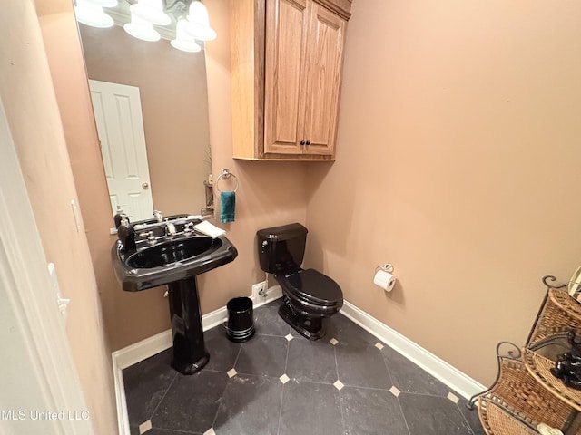 half bathroom with tile patterned floors, toilet, and baseboards